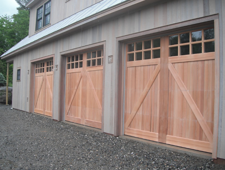 A row of wooden garage doors on the side of a house.