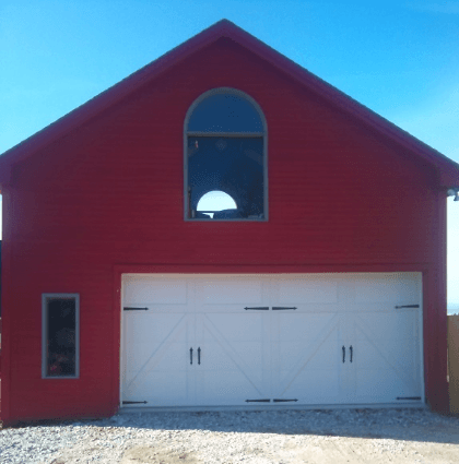 A red building with a white garage door and a window
