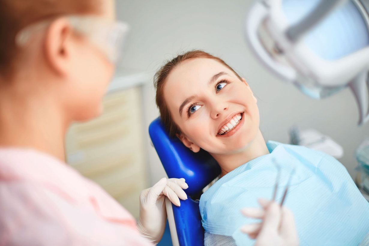 Woman in dentist chair smiles at dentist.