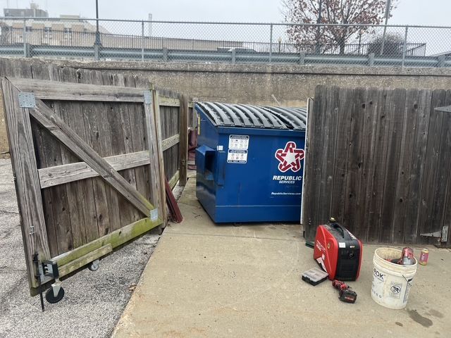 Chain-link fence beside blue dumpster