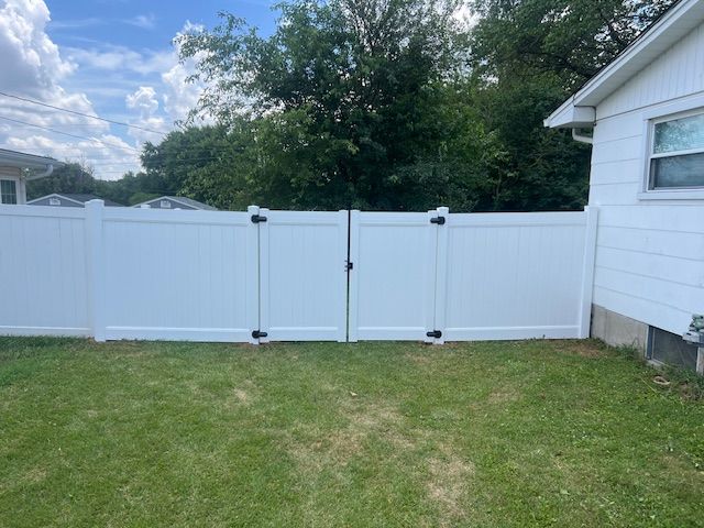 White vinyl fence across grassy backyard under cloudy sky