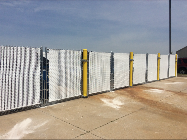 Chain-link fence with yellow posts along a concrete lot under a clear sky