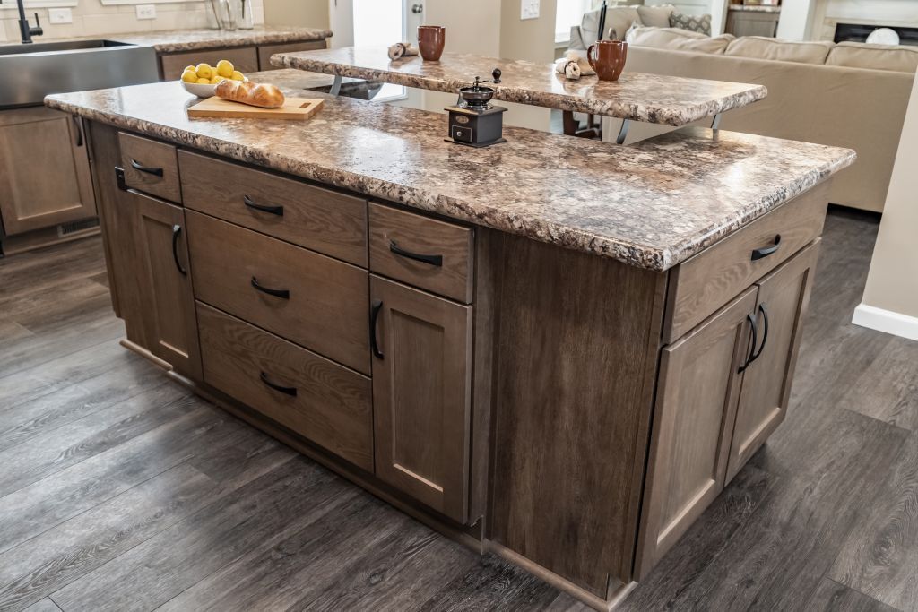 Brown kitchen island with granite countertop and wood cabinets in a home.