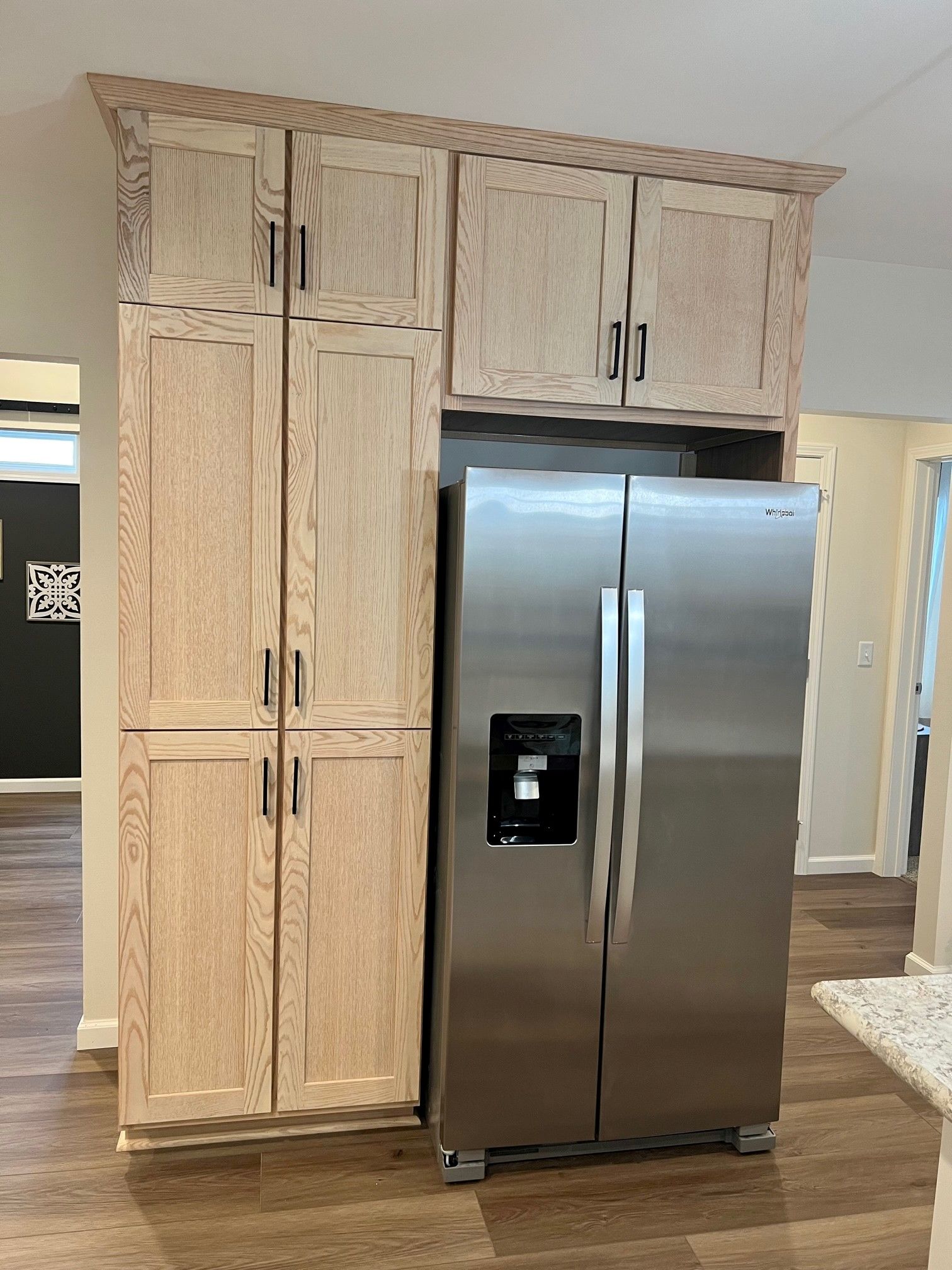 Tall wooden cabinets and stainless steel refrigerator in kitchen.
