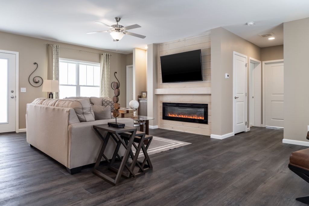 Living room with fireplace, TV, couch, dark wood floor, and light beige walls.