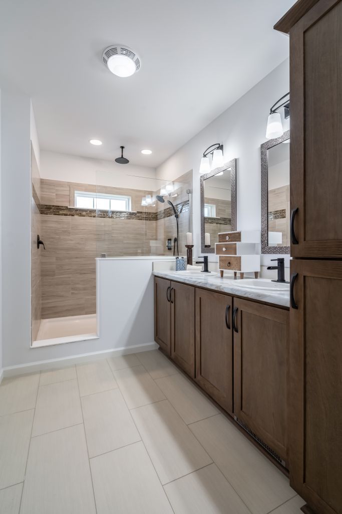 Bathroom with double vanity, shower, neutral colors, and wooden cabinets.
