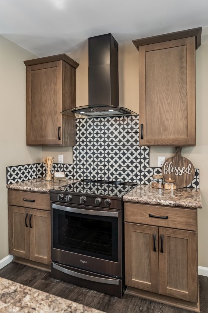Kitchen with wooden cabinets, a black oven, patterned backsplash, and a range hood.