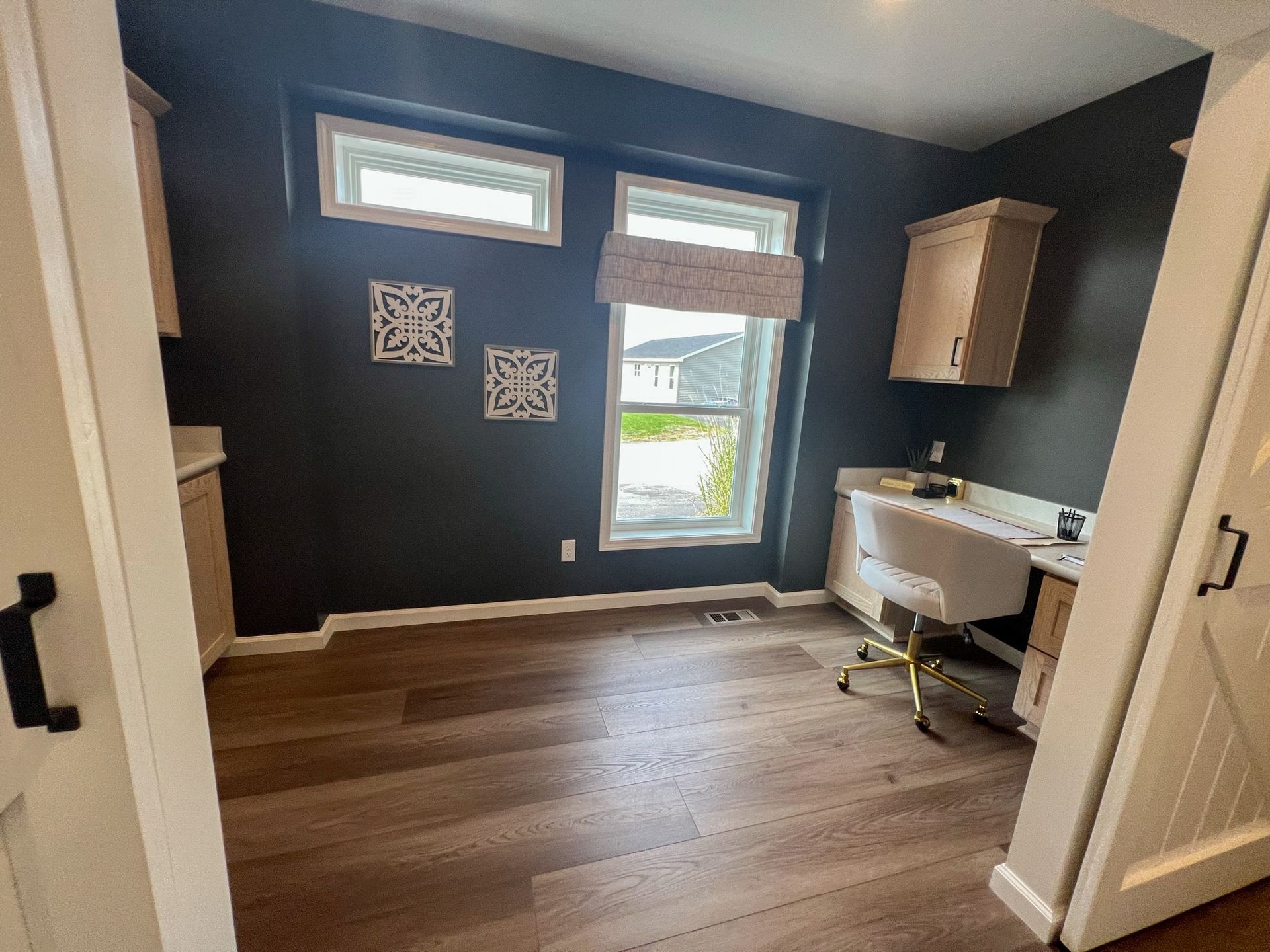 A room with a desk and chair in it and a window.