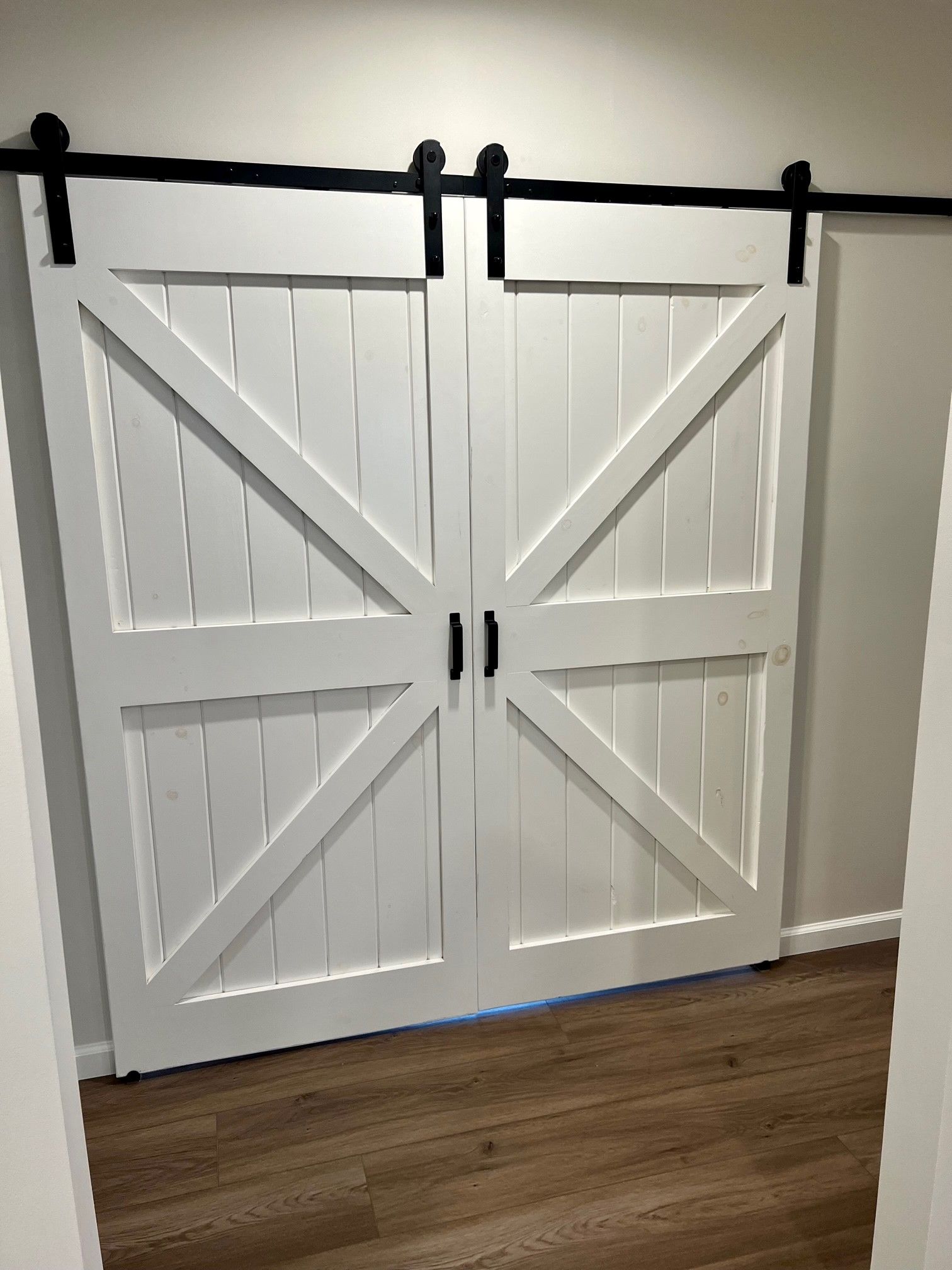 A pair of white sliding barn doors with a black railing.