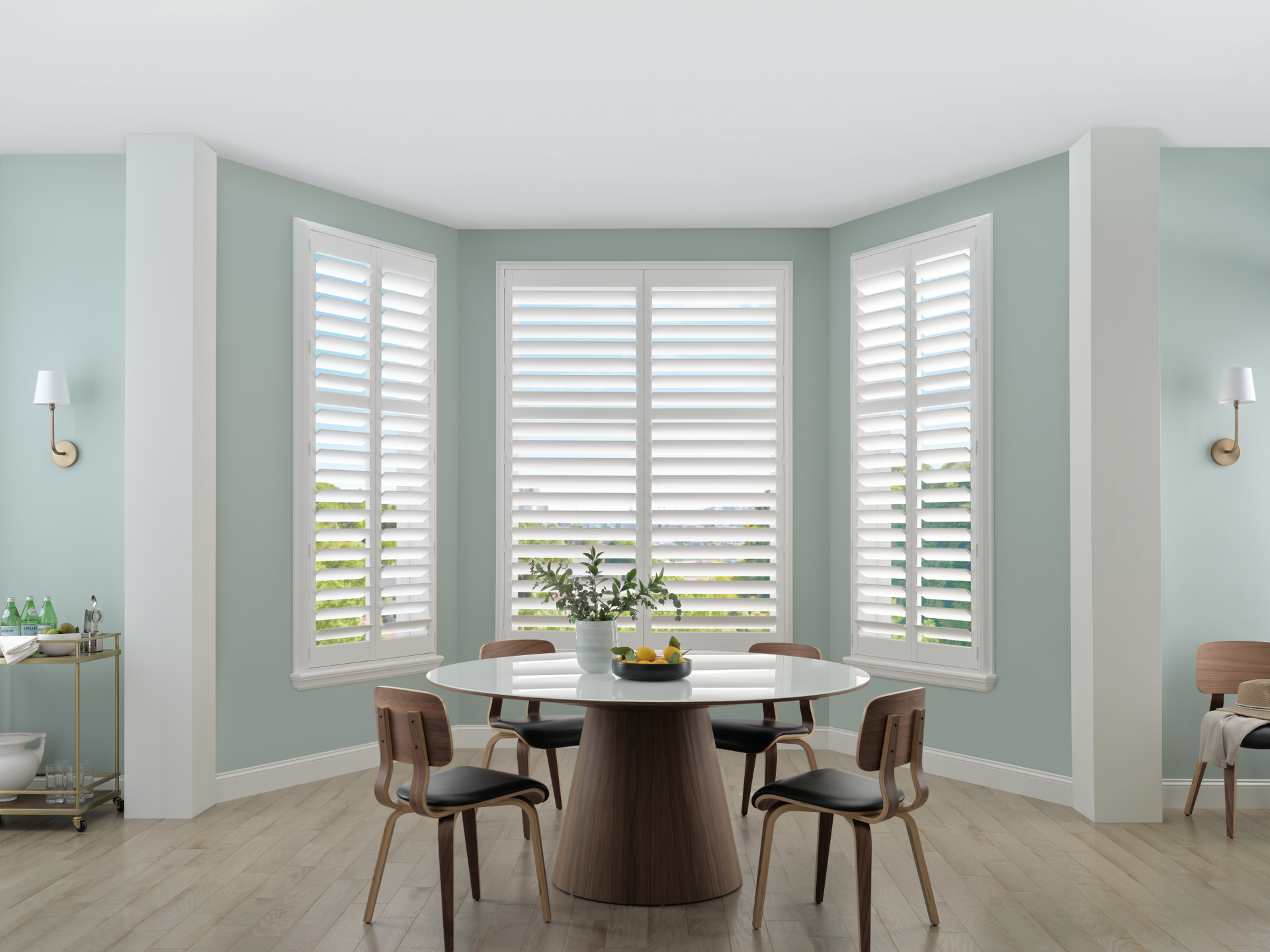 Bright dining nook with a round table, four chairs, bay windows, and pale green walls
