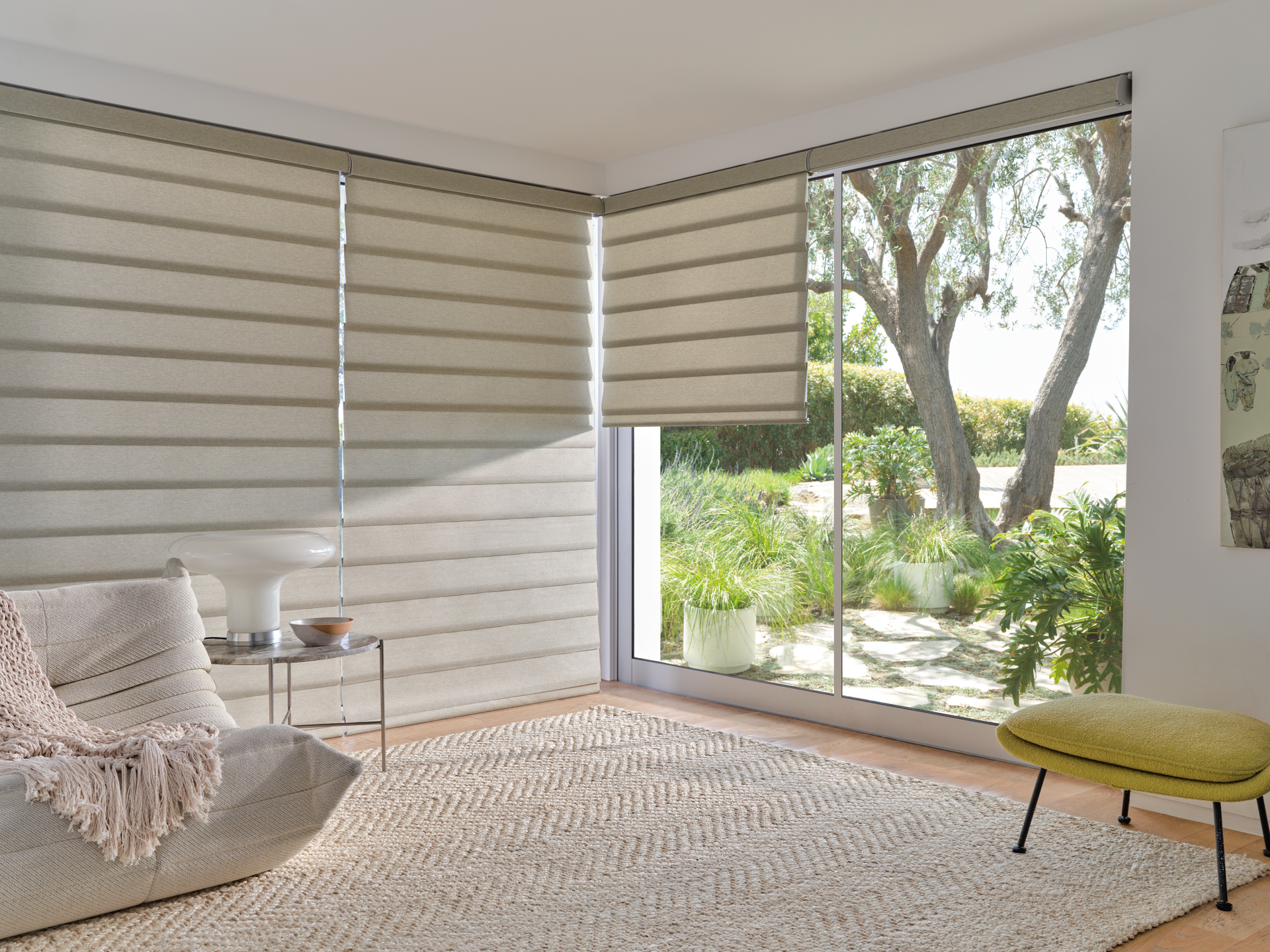Bright living room with striped blinds, a cozy chair, and large windows overlooking a garden