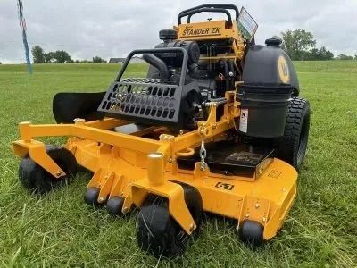 A yellow Stand-On ZK zero-turn commercial mower parked on a green, grassy field.
