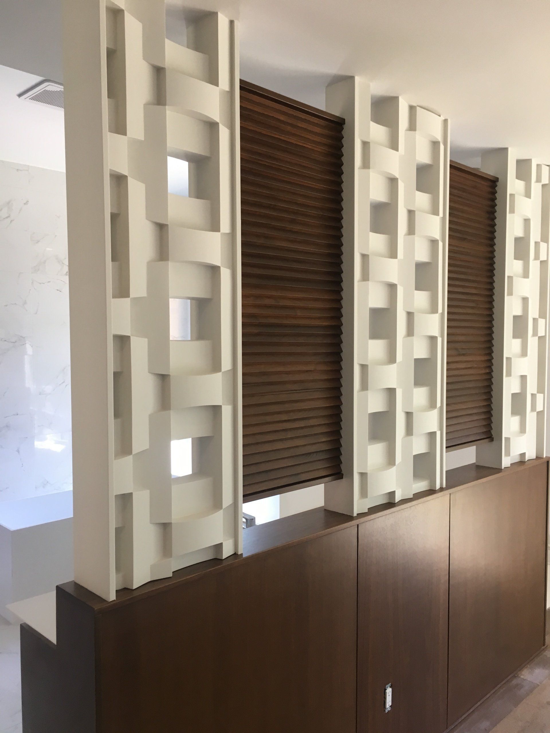 A room with a divider and wooden blinds on the windows.