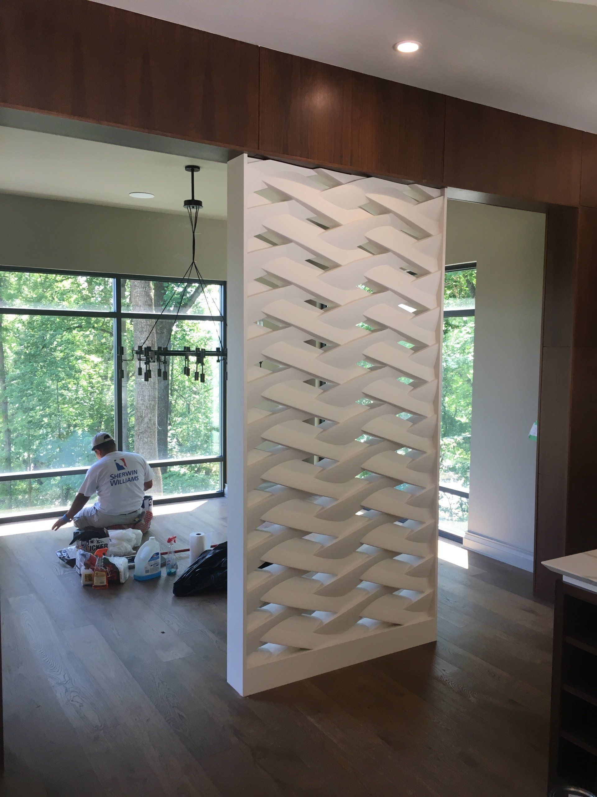 A man in a white shirt is sitting on the floor in front of a window.