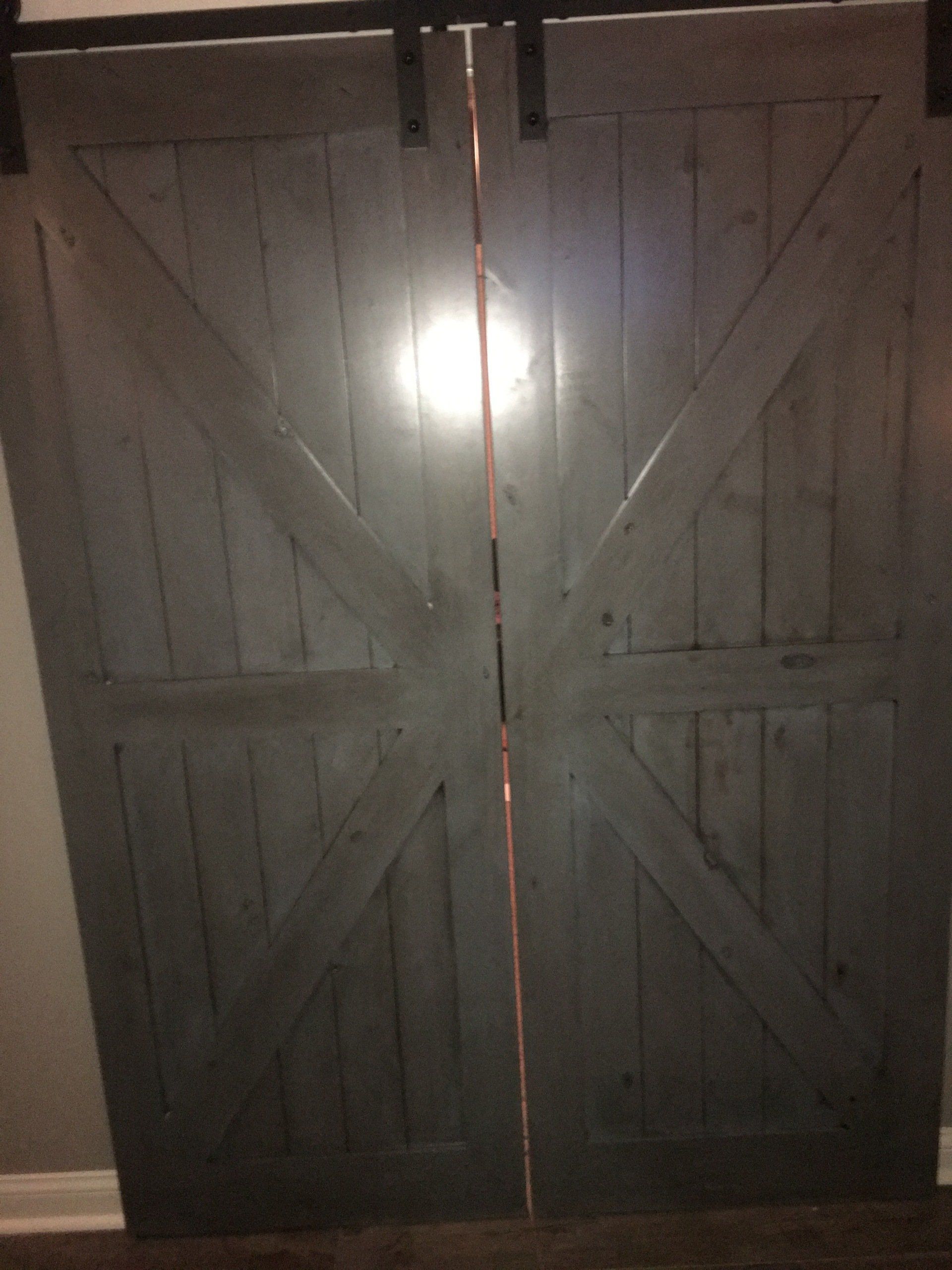 A pair of sliding barn doors with a light shining through them