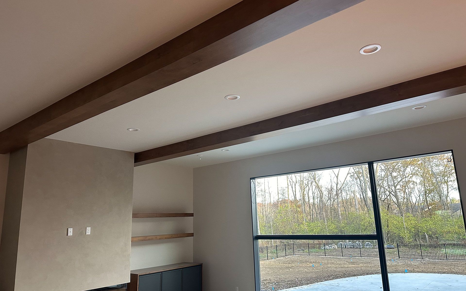A living room with a large window and a ceiling with wooden beams.