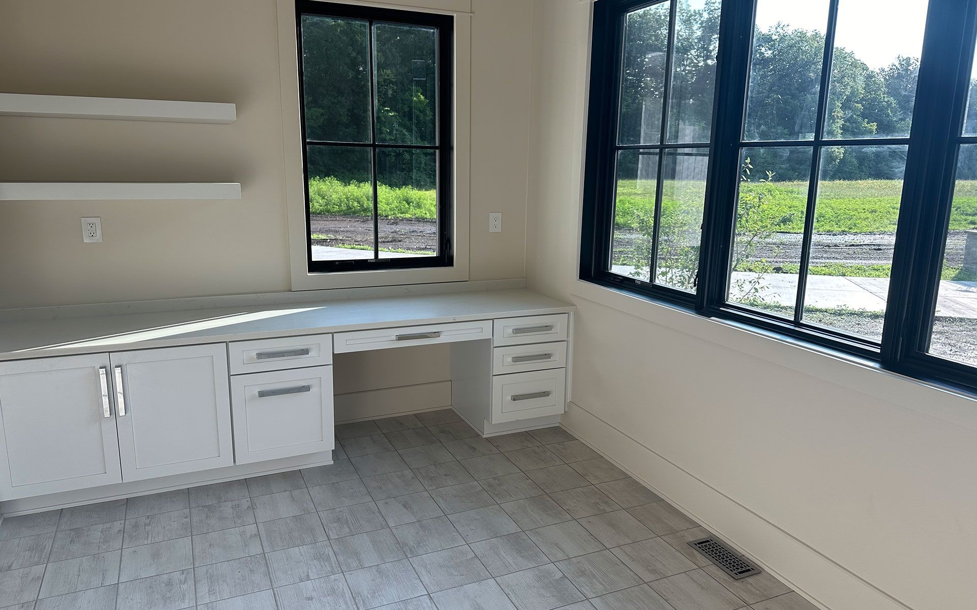 An empty room with a desk and two windows