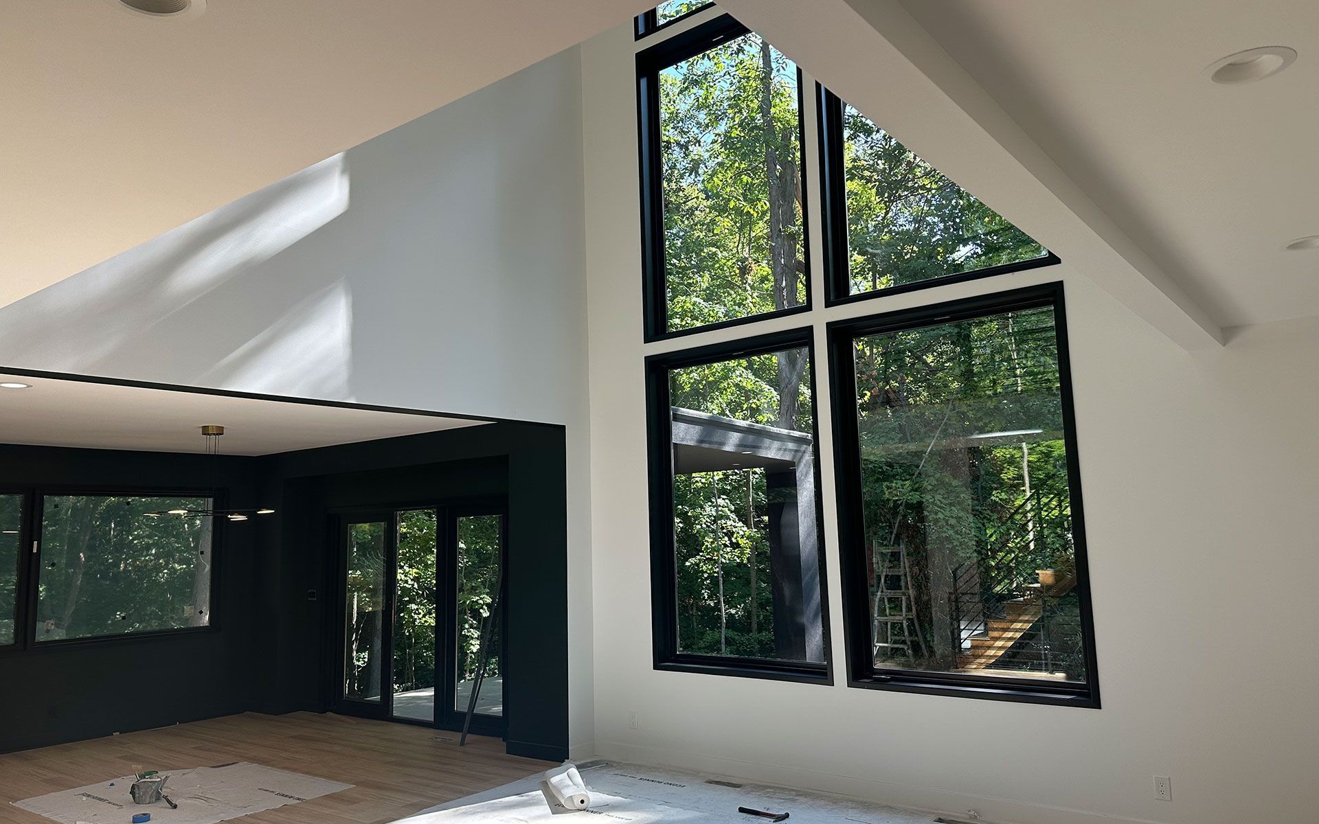 A living room with a lot of windows and trees in the background.