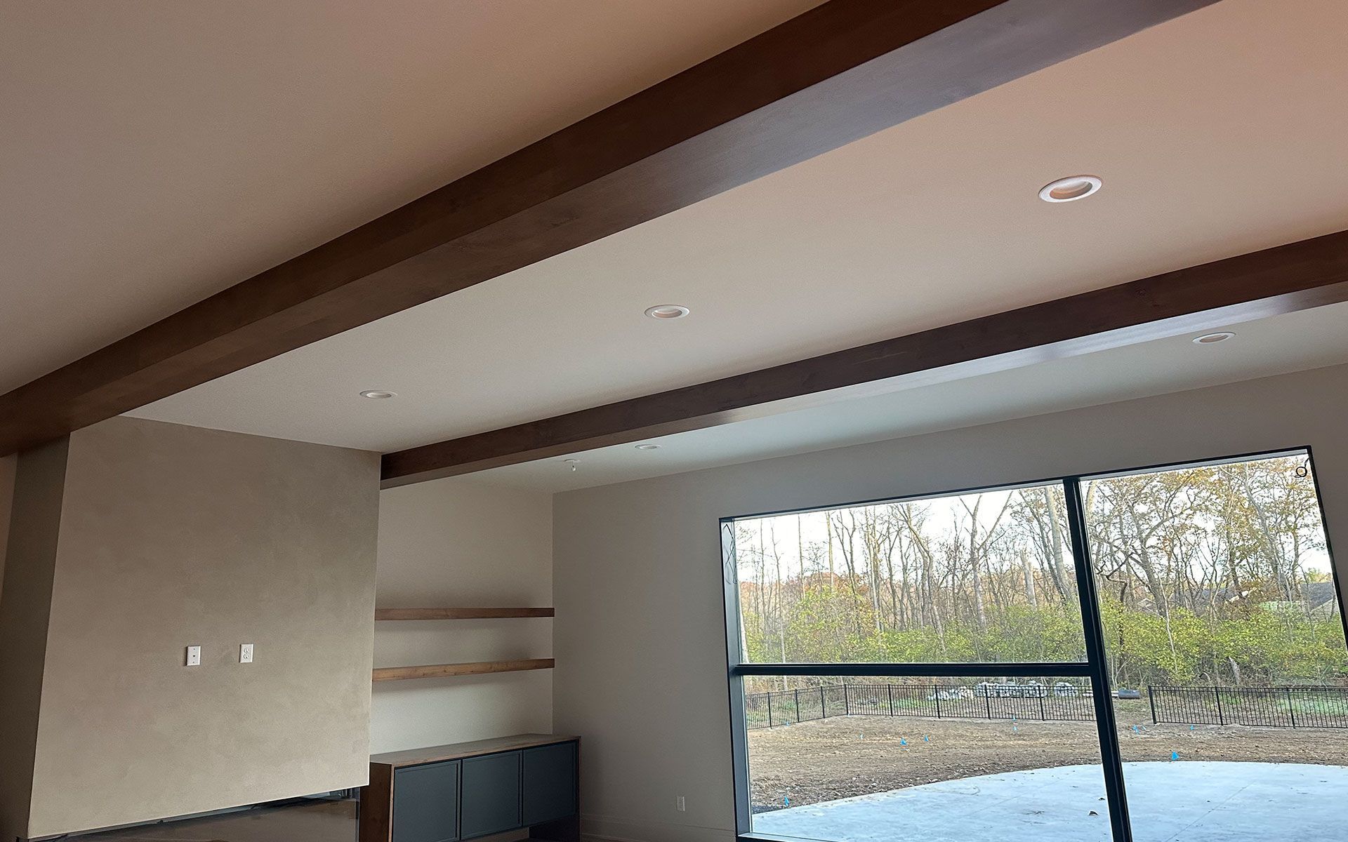 A living room with a large window and wooden beams on the ceiling.