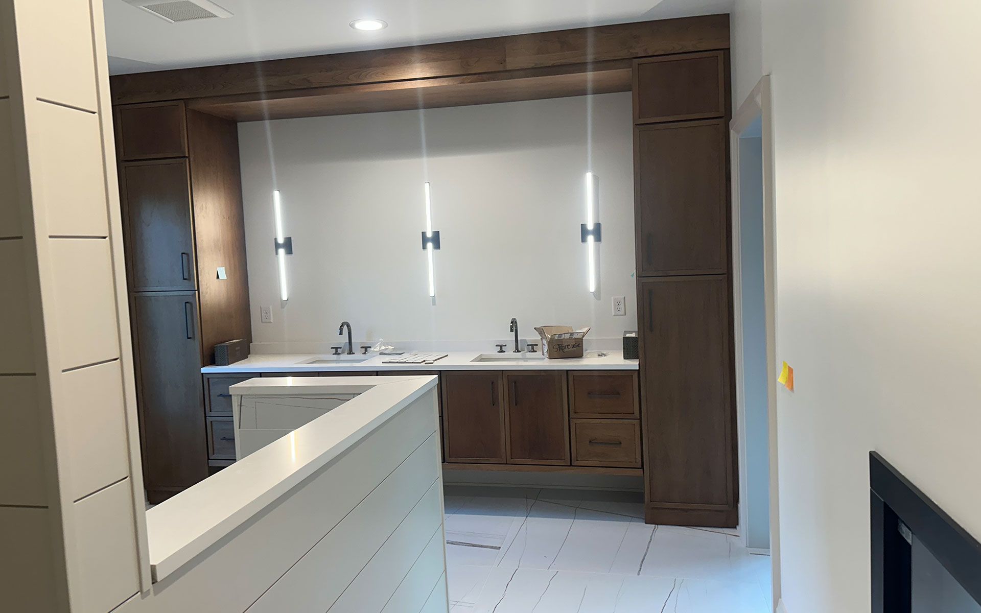 A kitchen with wooden cabinets , a sink , and a fireplace.