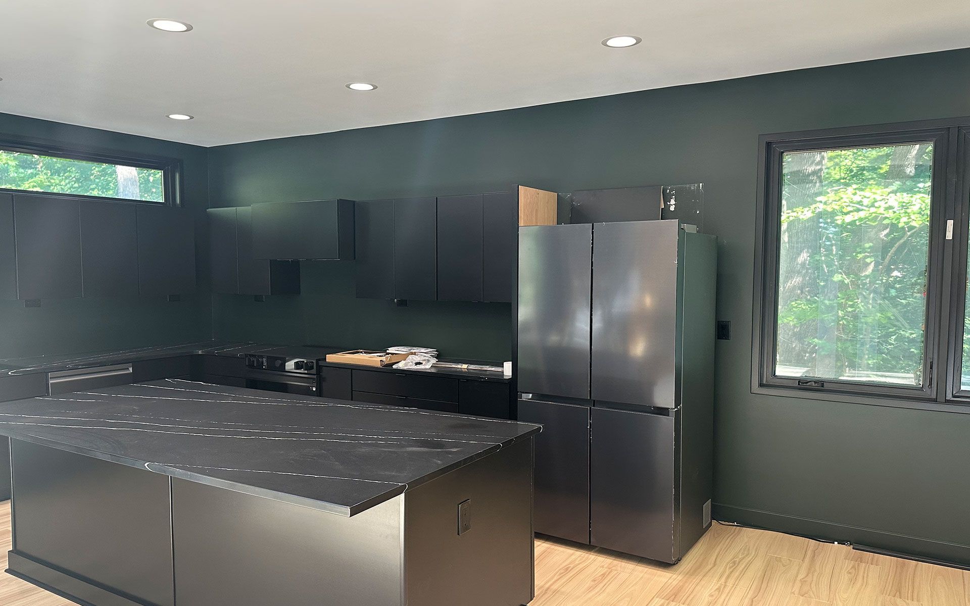 A kitchen with black cabinets and a black refrigerator.