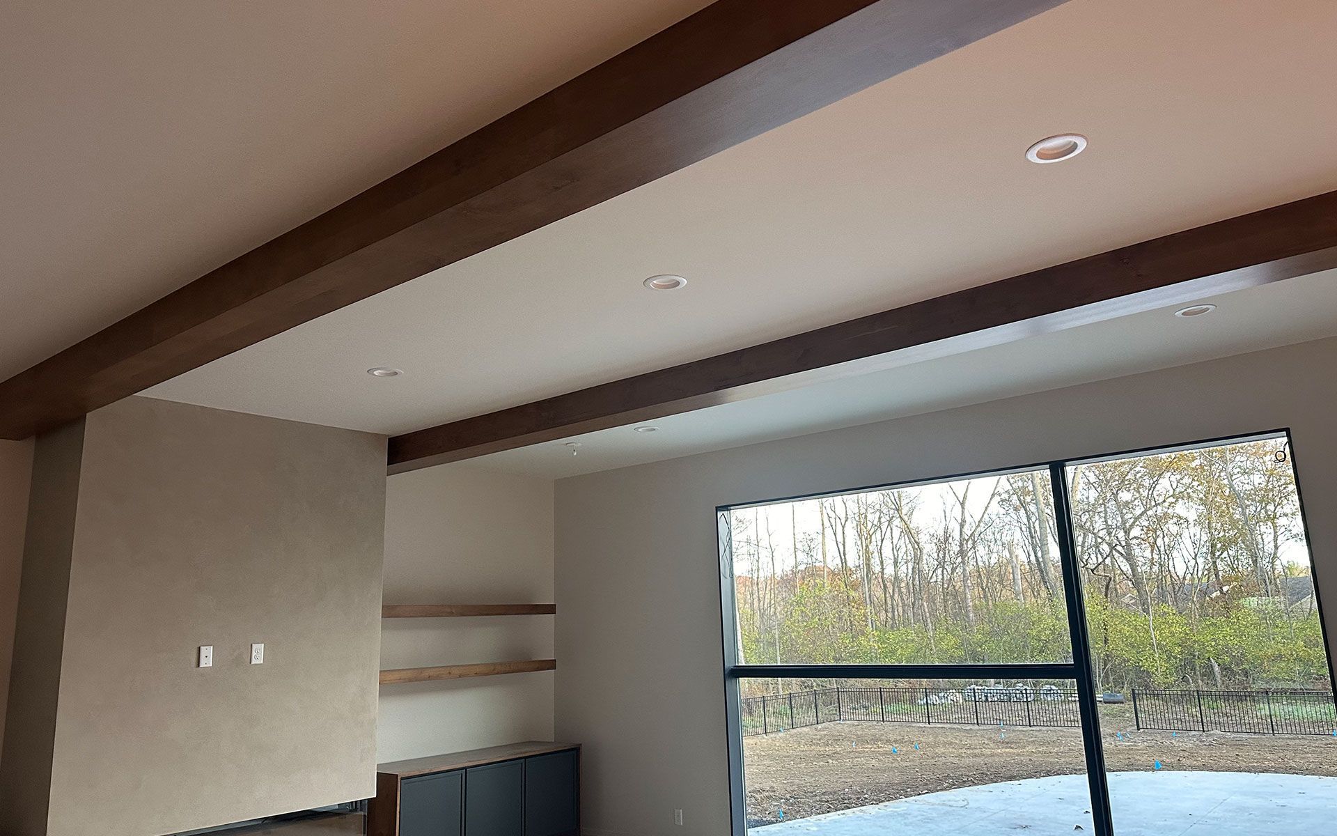 A living room with a large window and a ceiling with wooden beams.