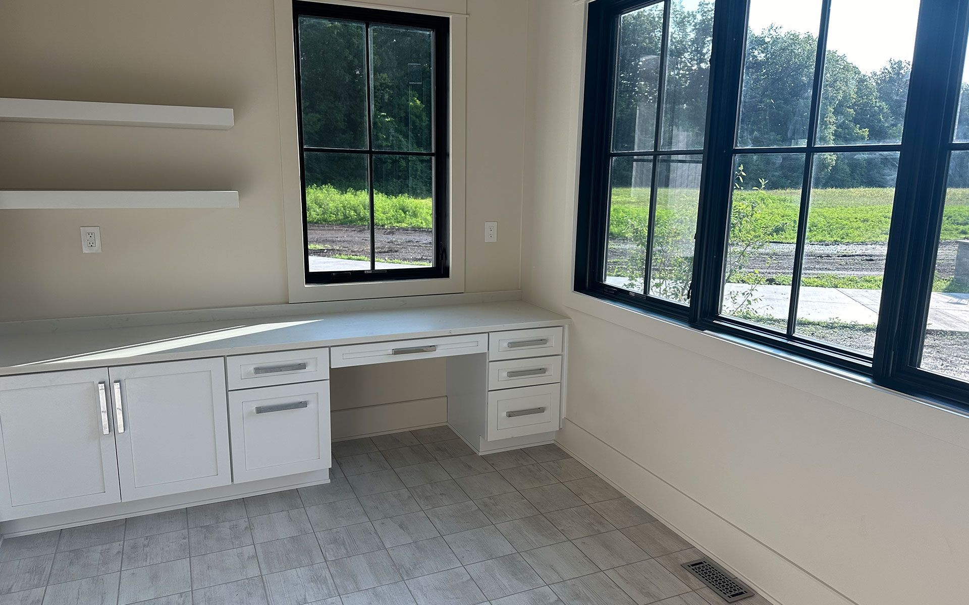 An empty room with a desk and two windows