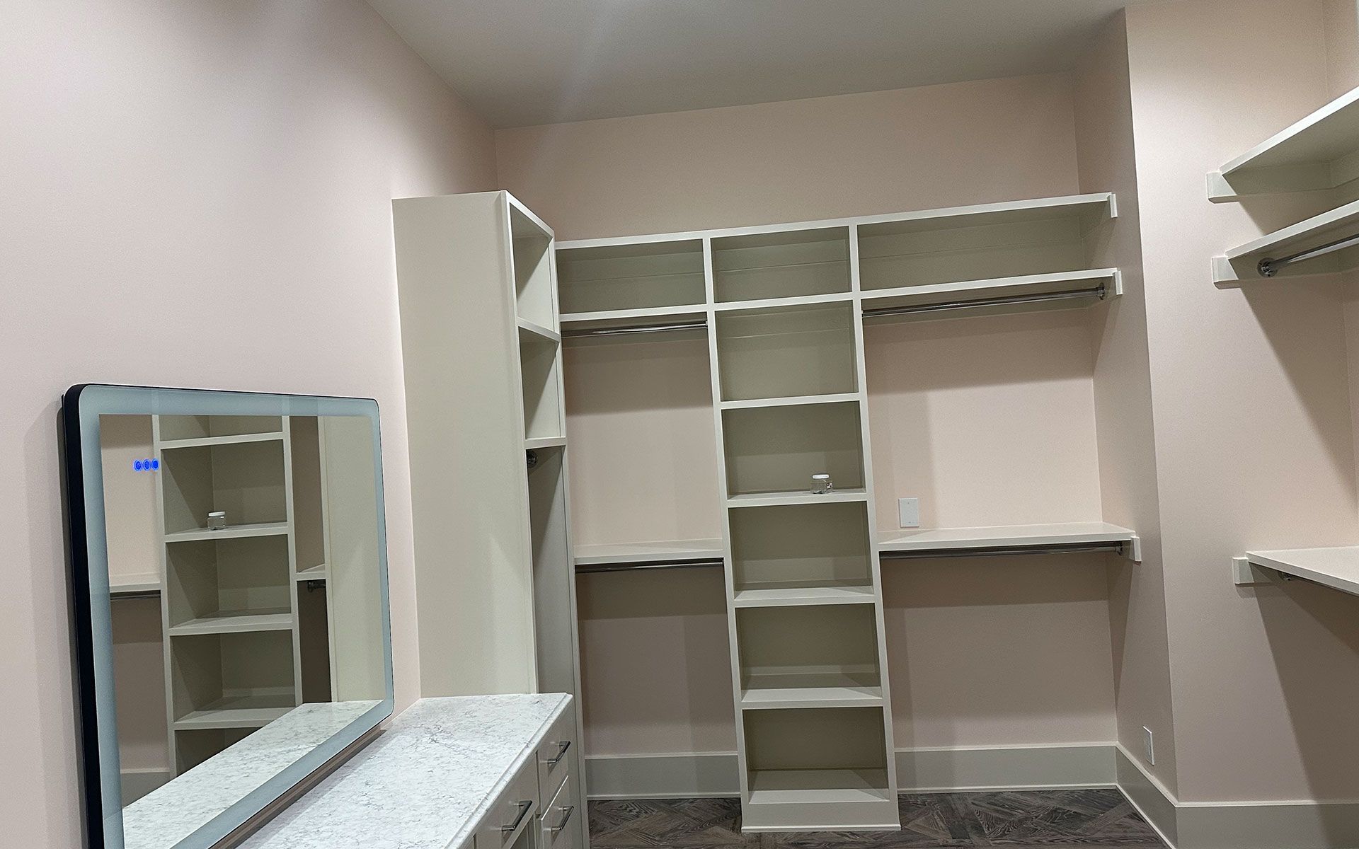 A walk in closet with lots of shelves and a mirror.