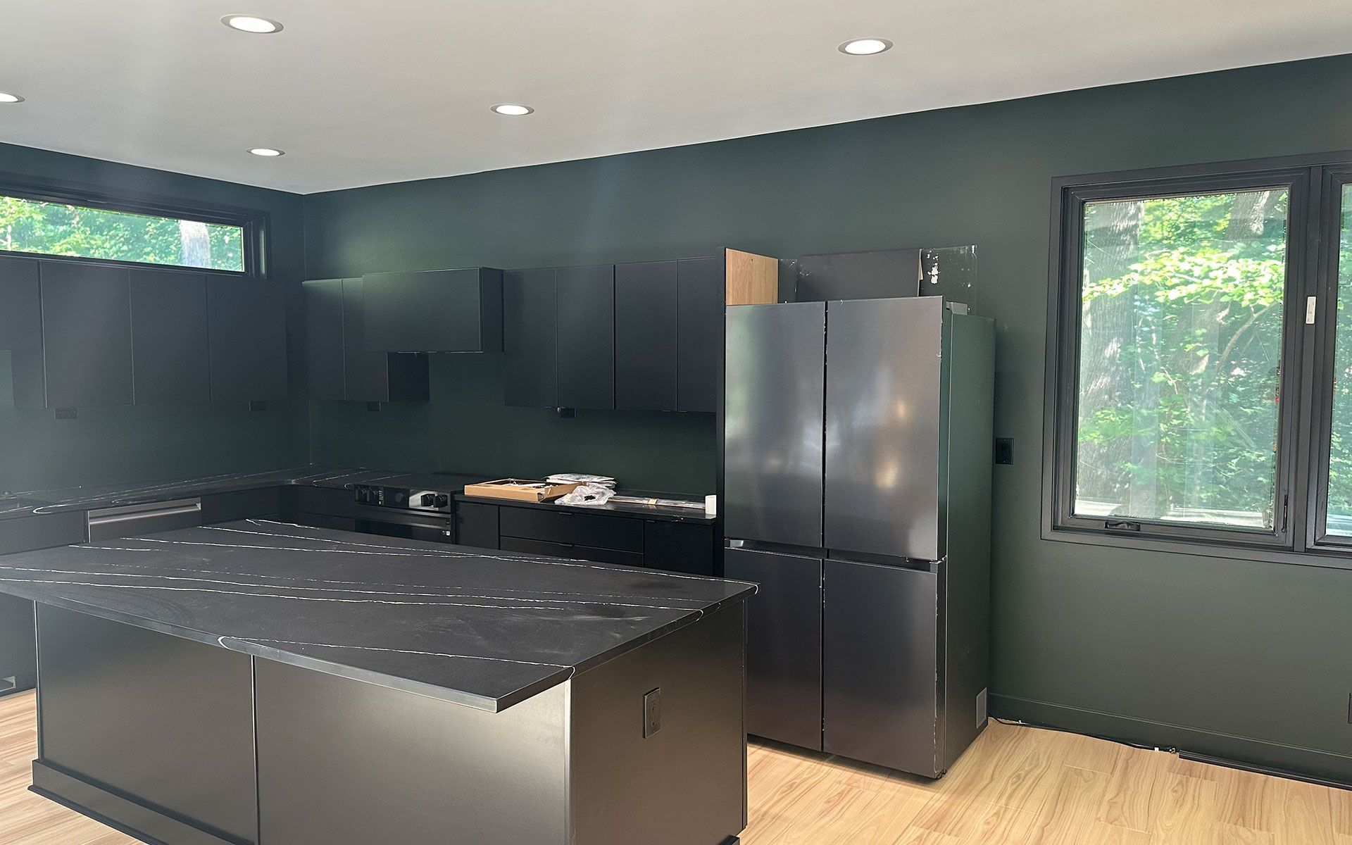 A kitchen with black cabinets and a black refrigerator.