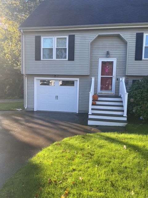 Gray two-story house with white trim, garage, and front steps beside a green lawn.