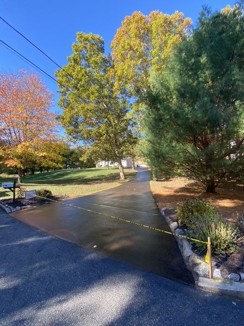Tree-lined driveway with autumn foliage and a closed gate under a bright blue sky