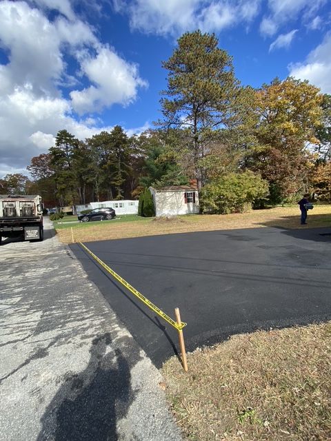 Empty paved lot beside mobile homes and autumn trees under a partly cloudy sky