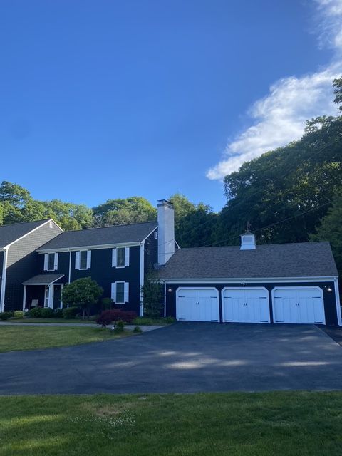 Suburban house with dark blue siding, white garage, and driveway under a bright blue sky