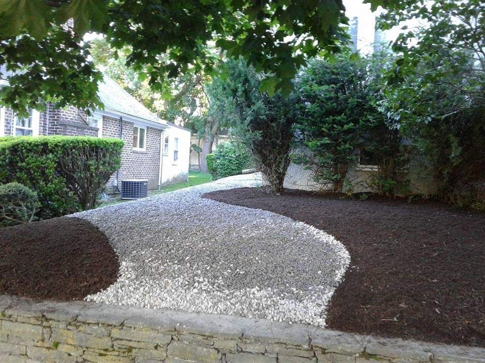 A gravel driveway leading to a house surrounded by trees and bushes