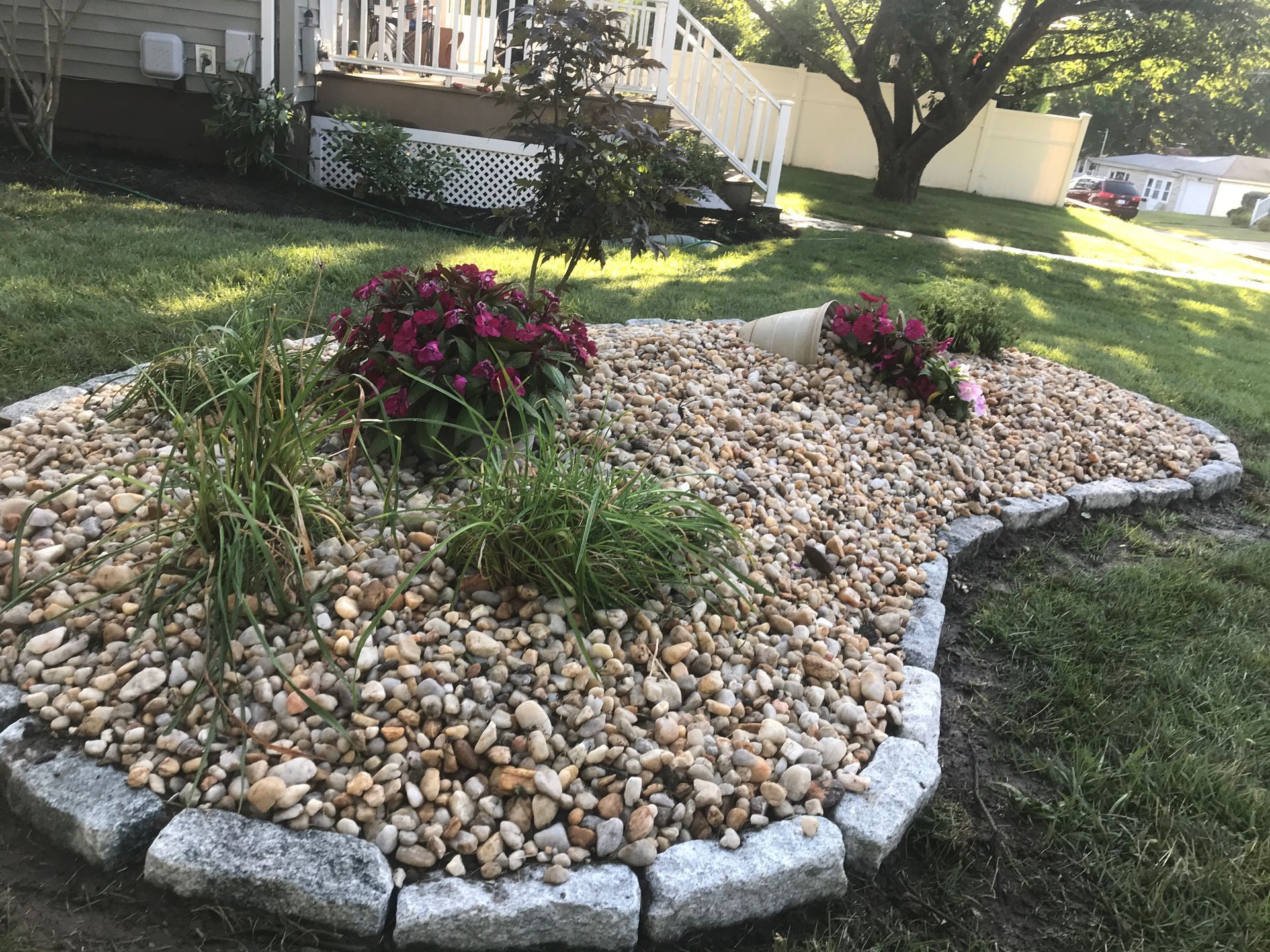 A garden filled with rocks and flowers in front of a house.