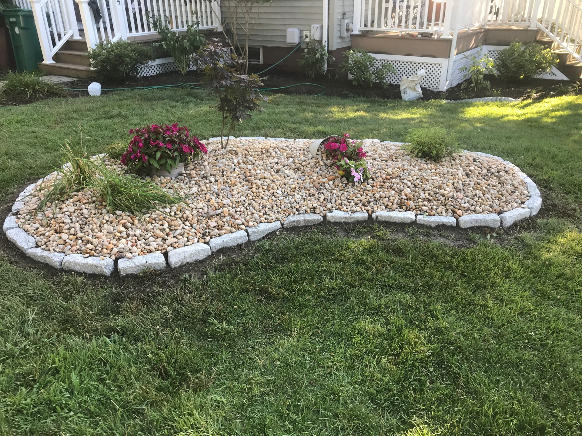 Garden bed with flowers and gravel in front of a house.