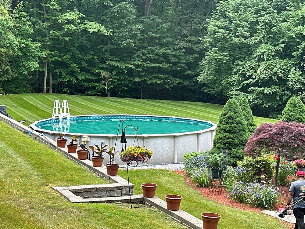 A lush green lawn in front of a house with a screened in porch.