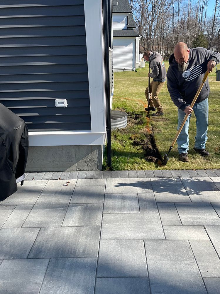A man is digging a hole in the grass with a shovel.