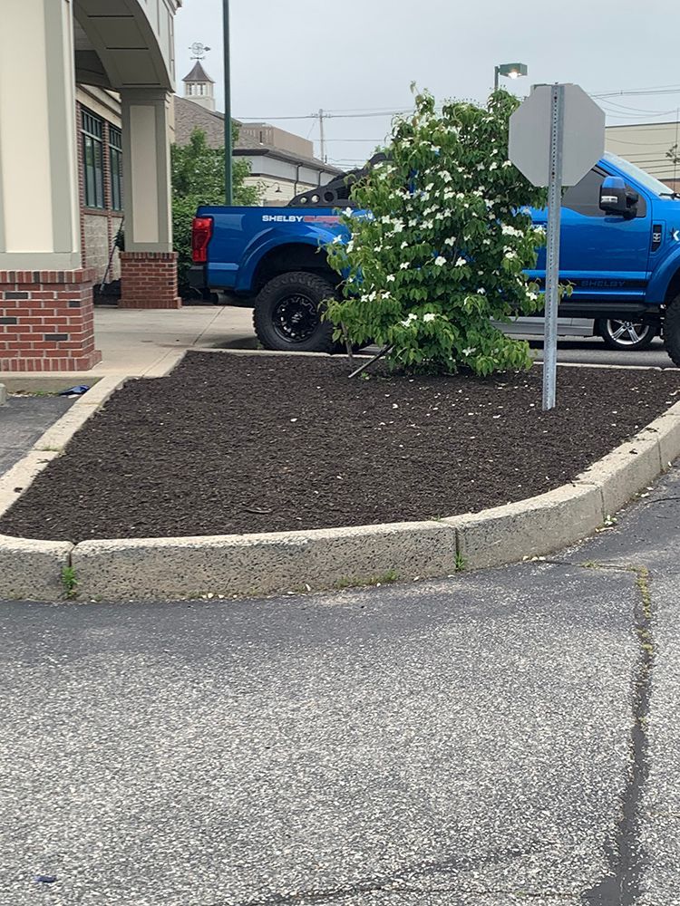 A blue truck is parked in a parking lot next to a sign.