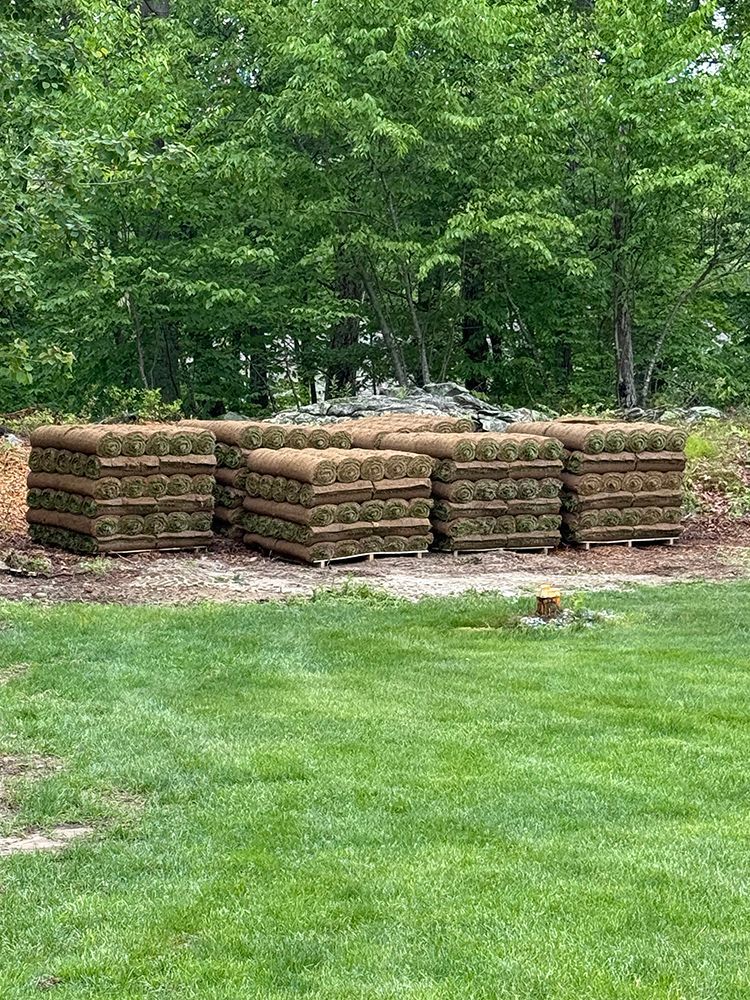 A stack of rolls of turf sitting on top of a lush green lawn.