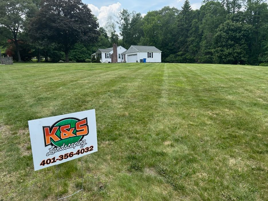 A k & s sign is in the middle of a lush green field.