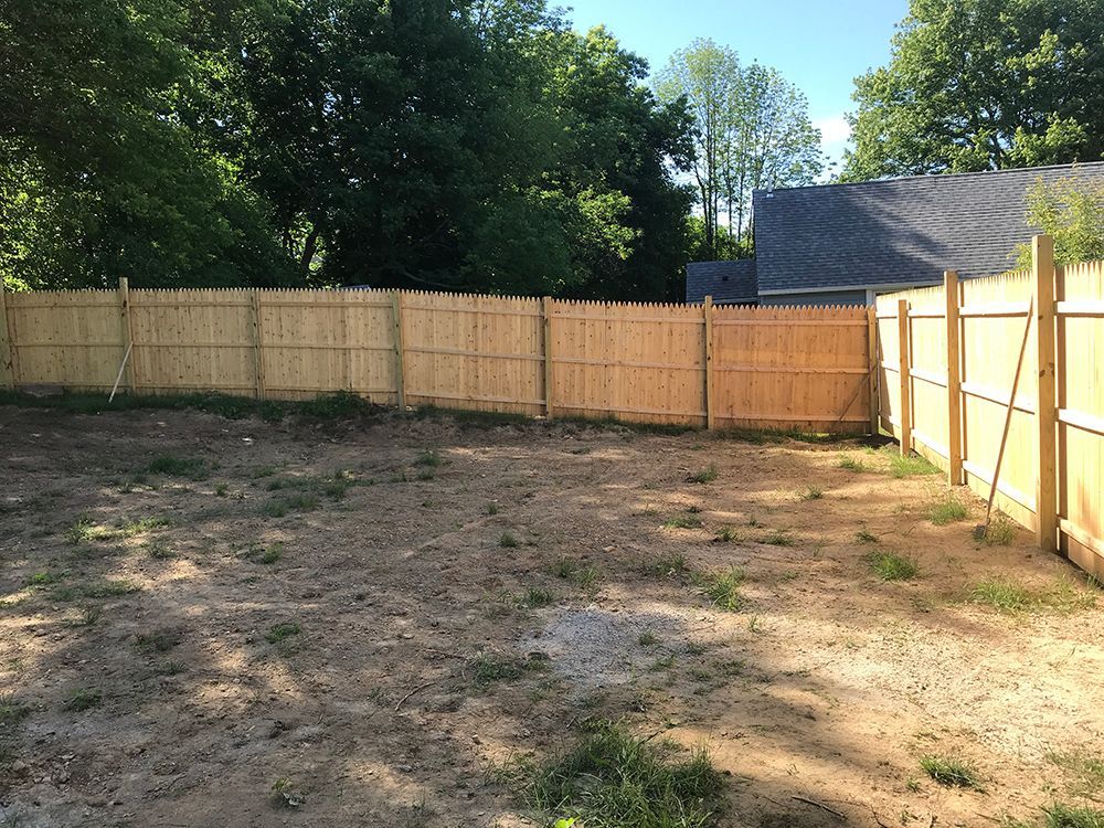 There is a wooden fence in the middle of a dirt field.