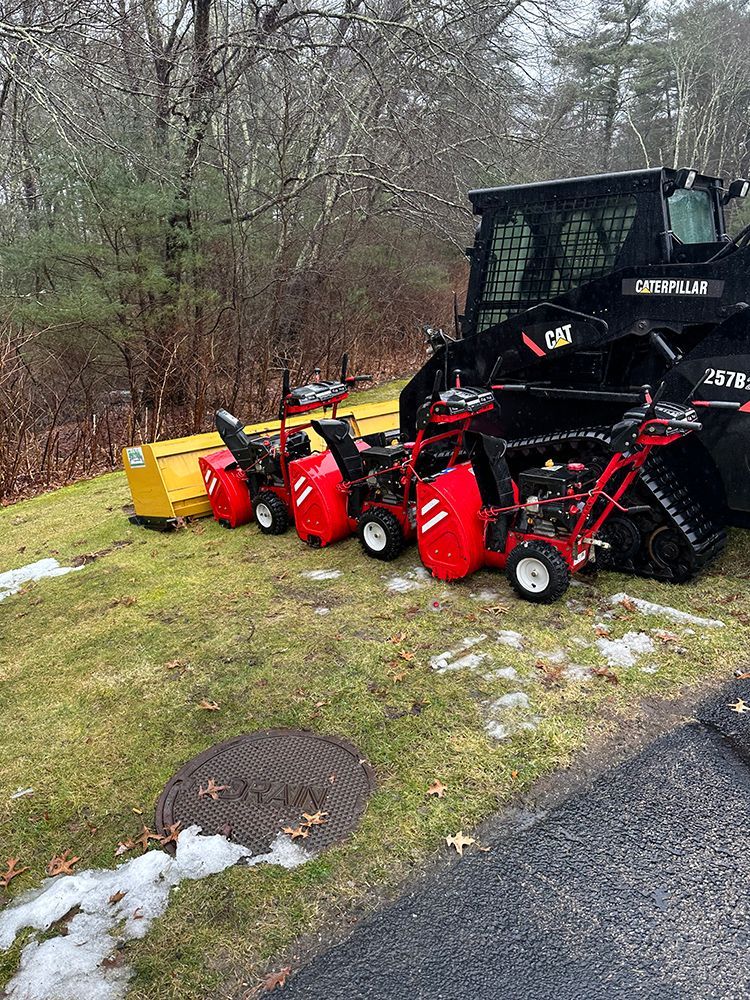 A row of snow blowers are parked on the side of the road.