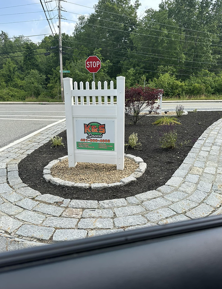 A stop sign is sitting in the middle of a brick walkway.