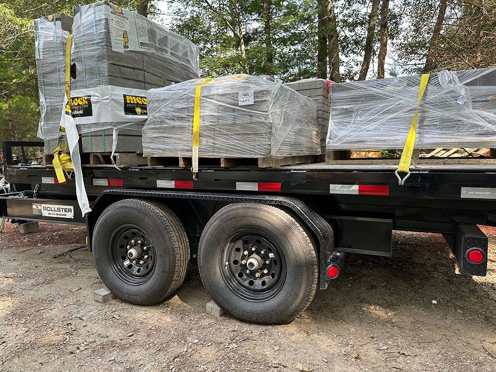 A trailer with a load of bricks on it is parked in the dirt.
