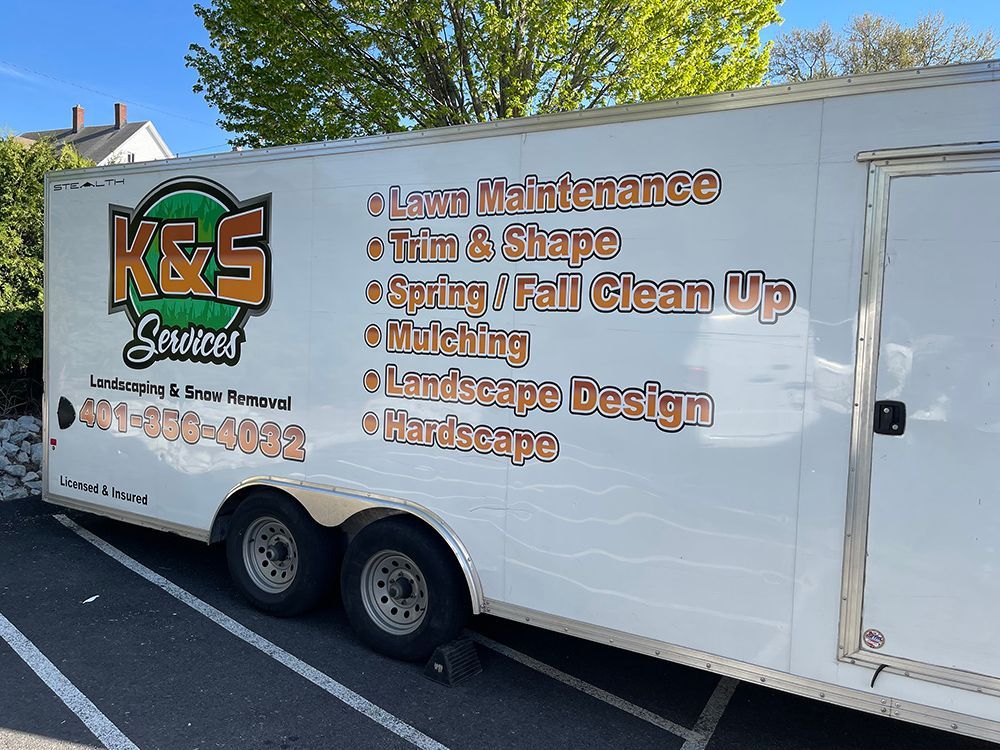 A k & s landscaping trailer is parked in a parking lot.