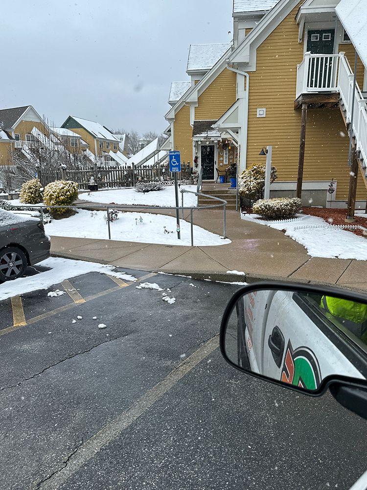 A car is parked in front of a building with snow on the ground.