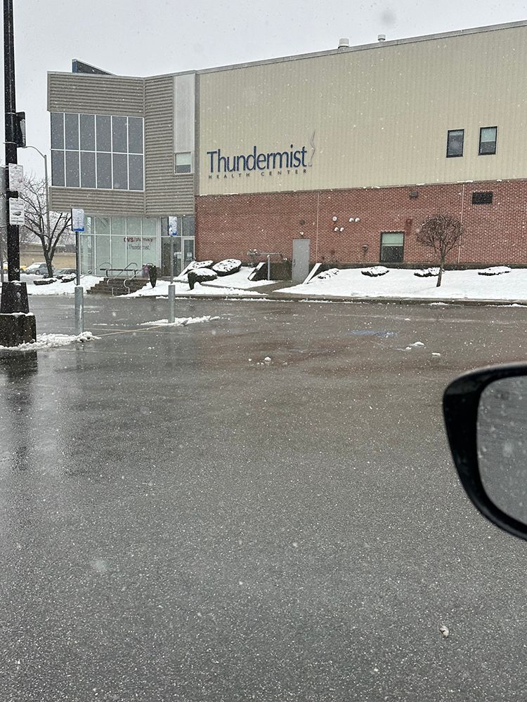 A car is parked in front of a building that says thundermist.