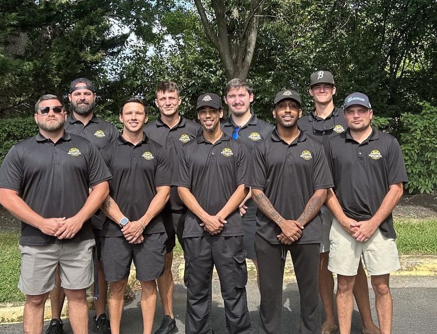 Group of people in black shirts and hats outdoors, posing for a photo.
