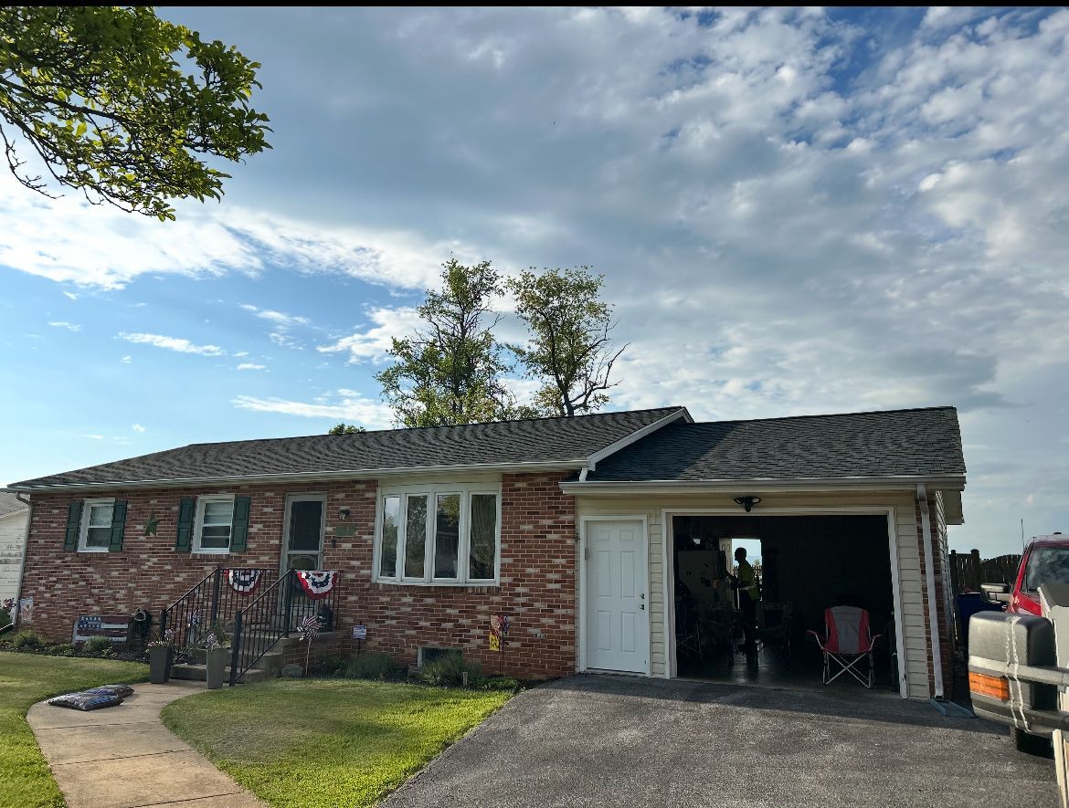 Brick house with garage, American flag decorations, and overcast sky.